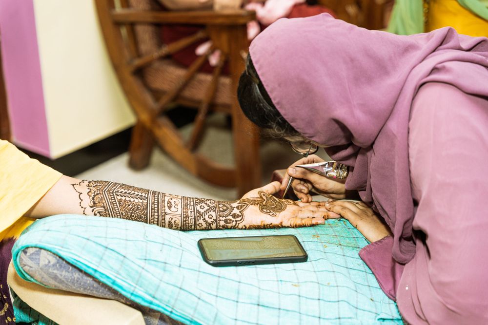 Close-up of intricate henna design being applied to a person's arm.
