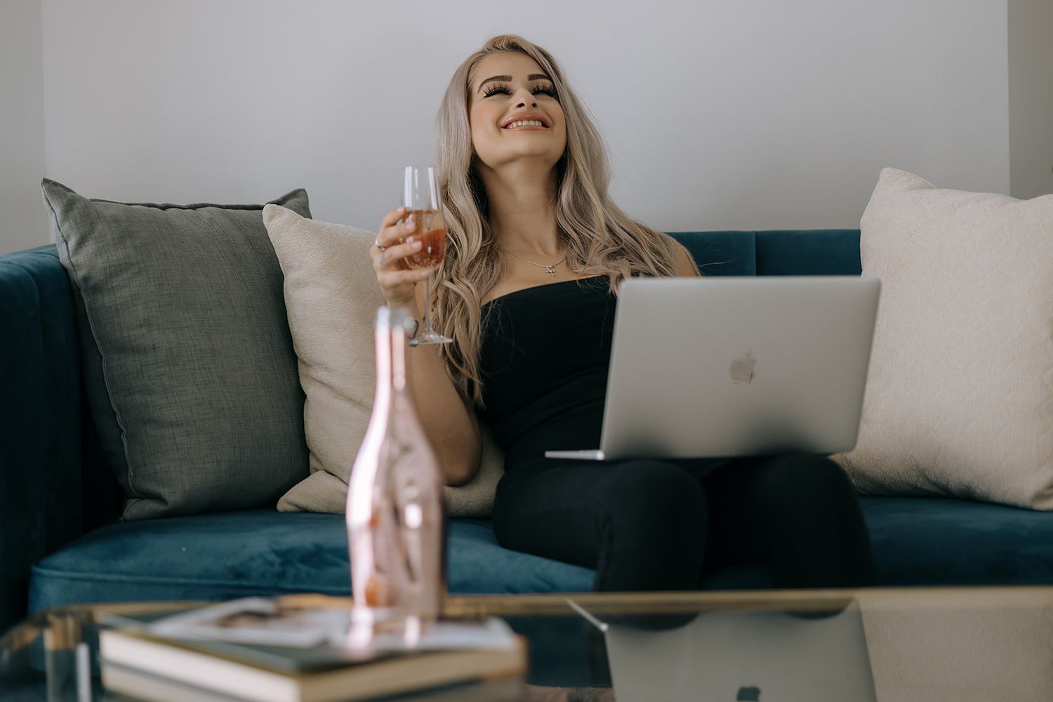 Client model with champagne watching her reveal slideshow on a Mac, laughing and loving her photos. Collingwood, ON