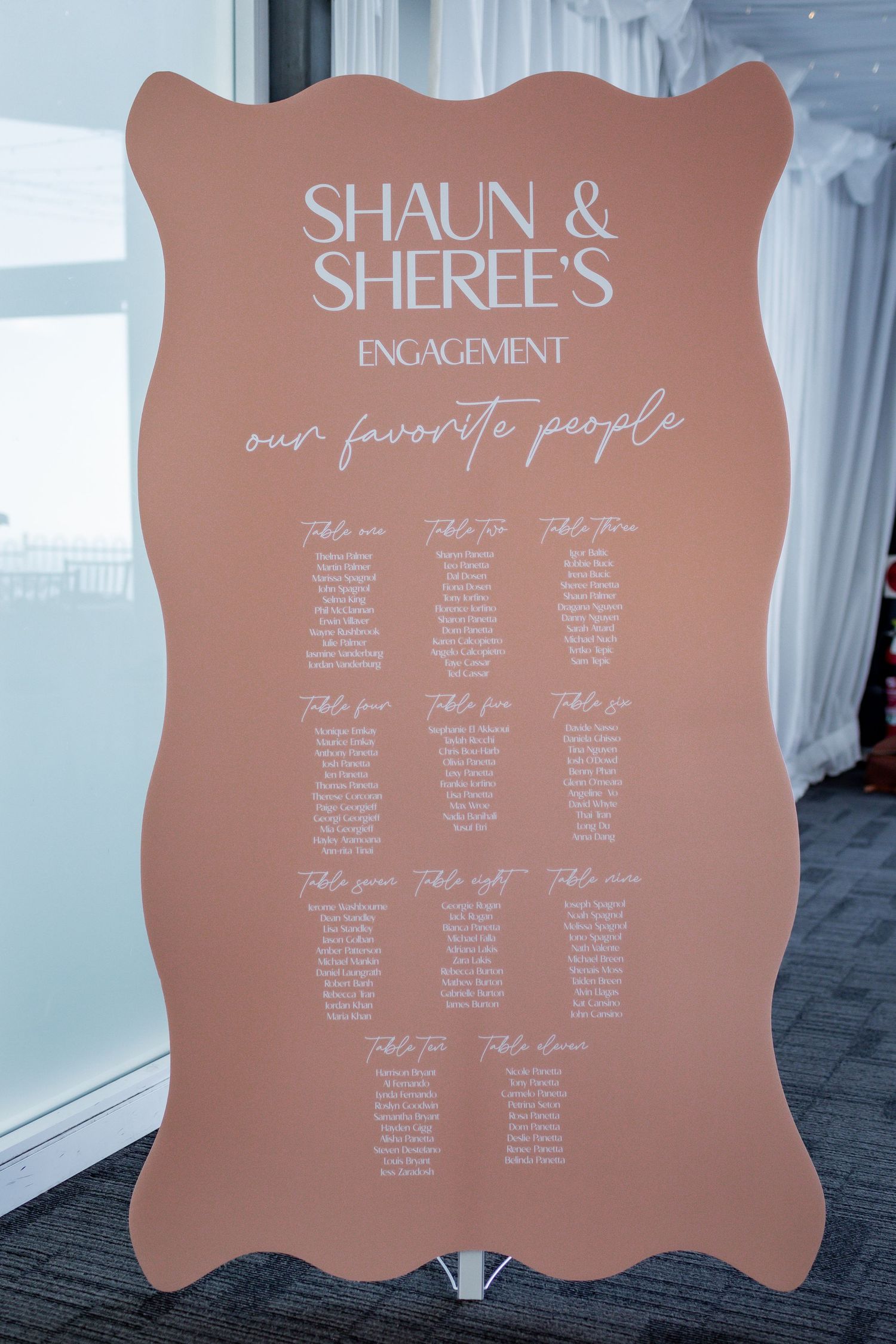 A mauve-colored seating chart sign displays 'Shaun & Sheree's Engagement' with table assignments for wedding guests.