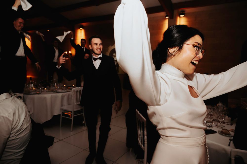 Wedding celebration with energetic dancing in a warmly lit reception venue.