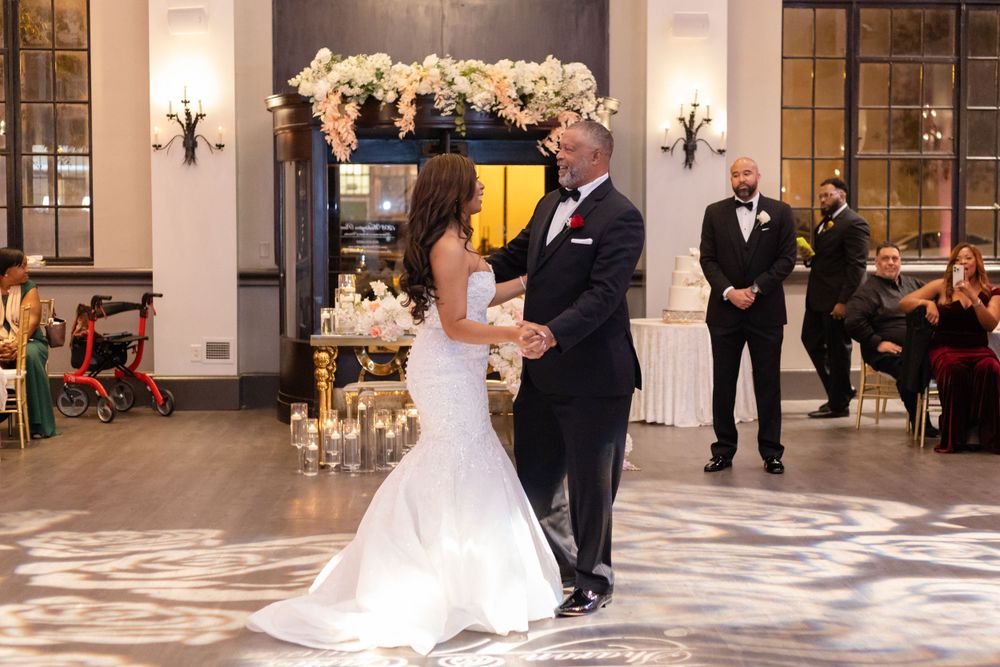 A couple shares their first dance in front of an elegantly decorated fireplace at their wedding reception.