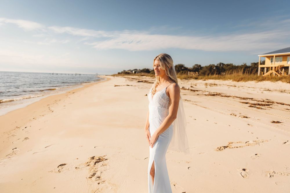A serene beach photoshoot featuring a white dress against sandy shores and ocean waves.