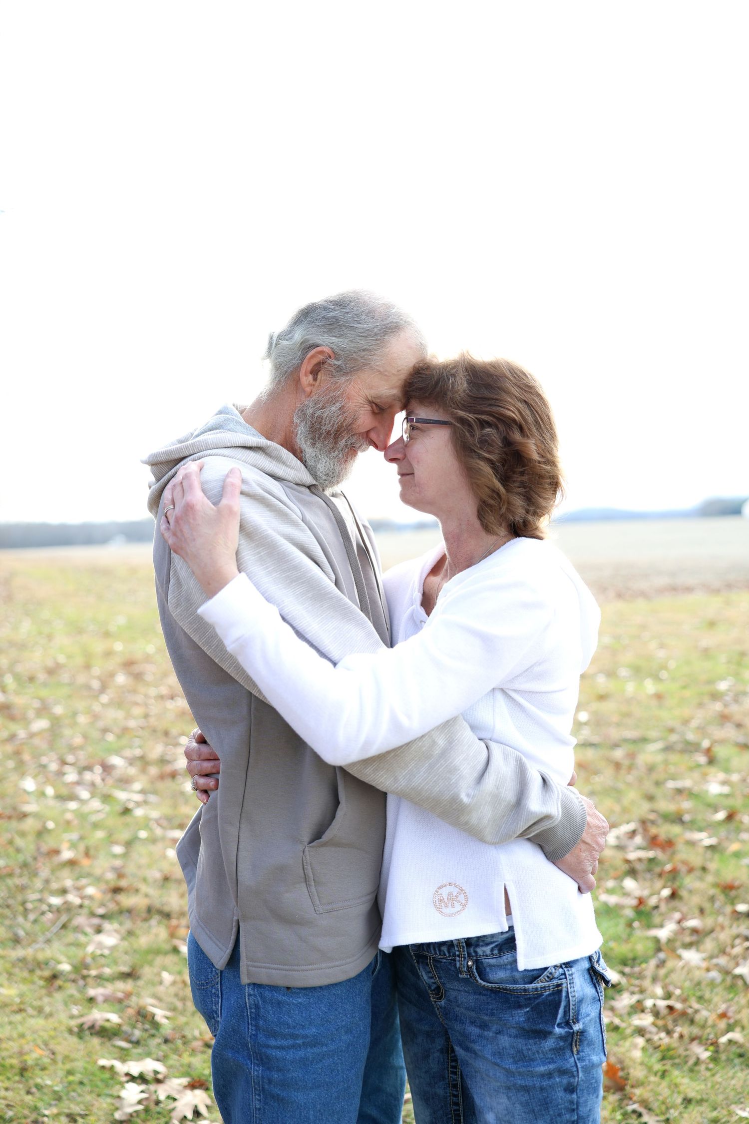 Couple hugging one another in a field.