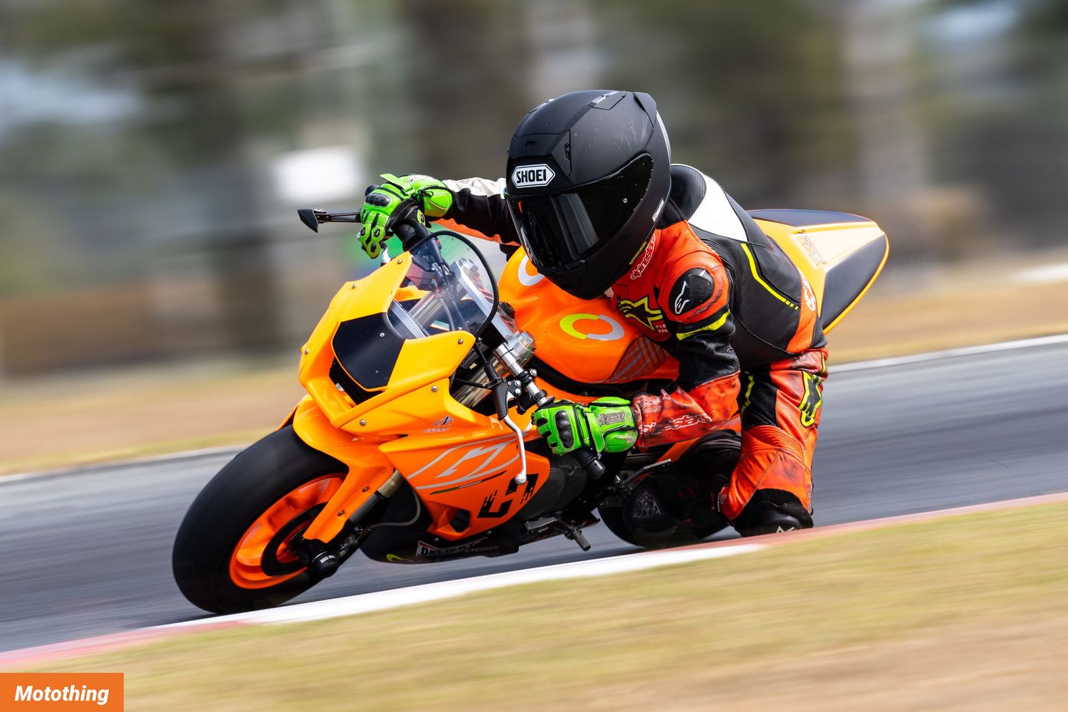 Rider in black gear pilots orange sport bike through corner on racetrack.