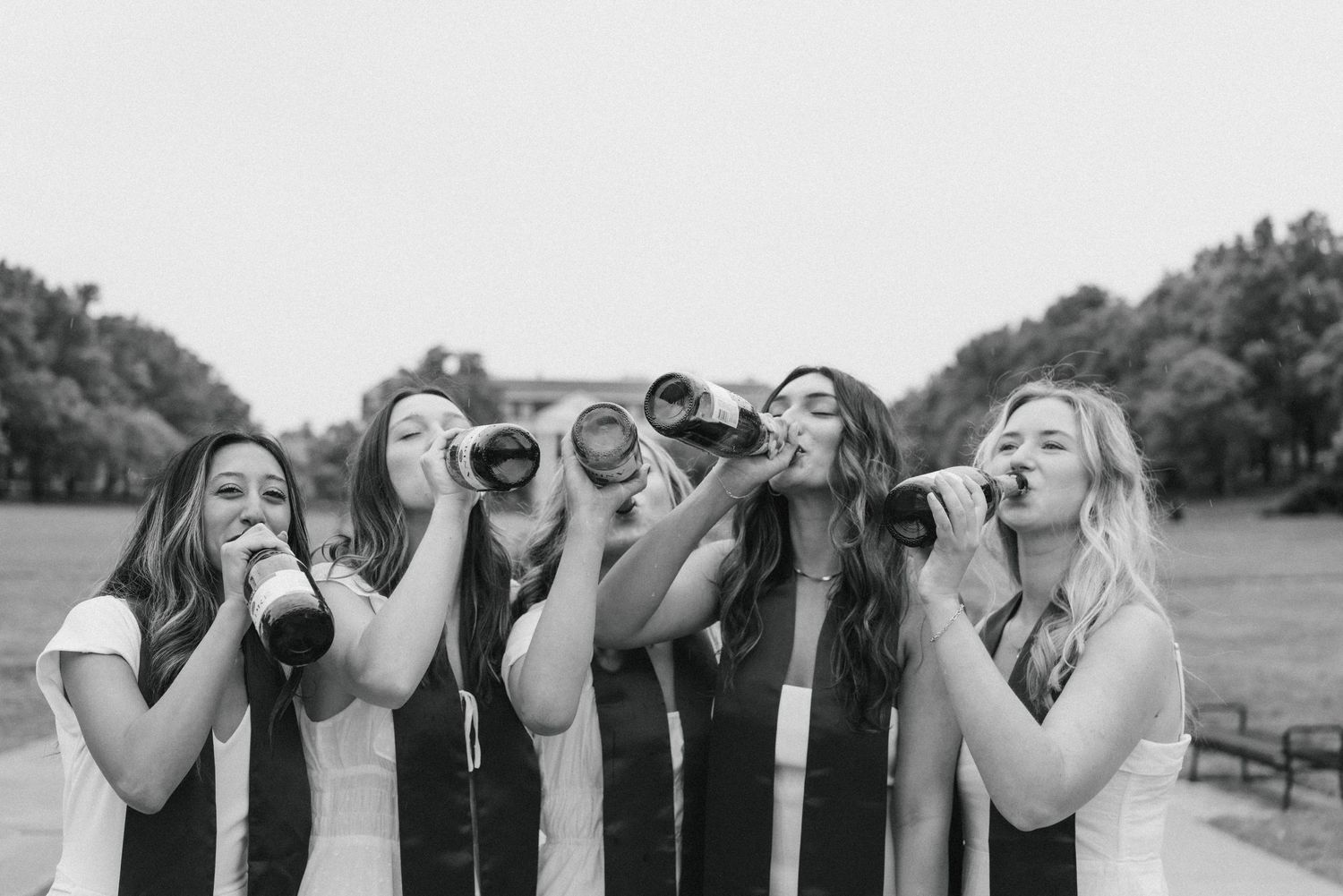 Row of friends making silly faces and posing together outdoors in black and white photography.