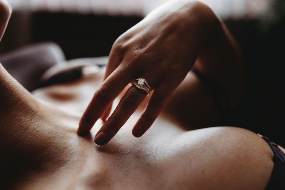 Elegant engagement ring on a finger with soft lighting and blurred background creating an intimate mood.