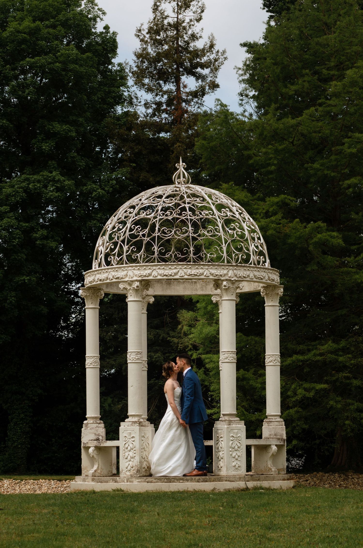 Elegant white stone gazebo in a garden setting perfect for wedding ceremonies.