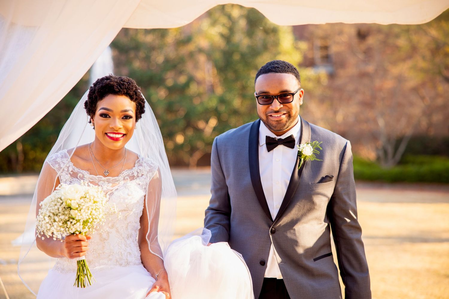 Joyful wedding couple walking outdoors during golden hour photography session.
