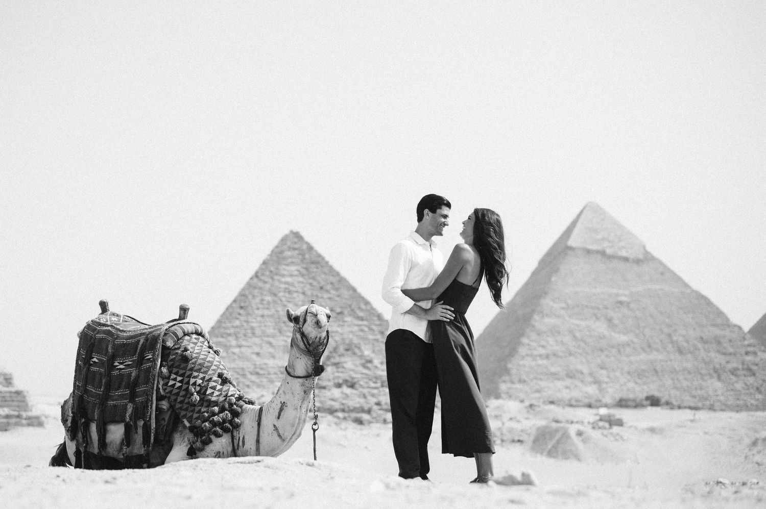 Love story photoshoot at the pyramids of Giza with camels in the background.