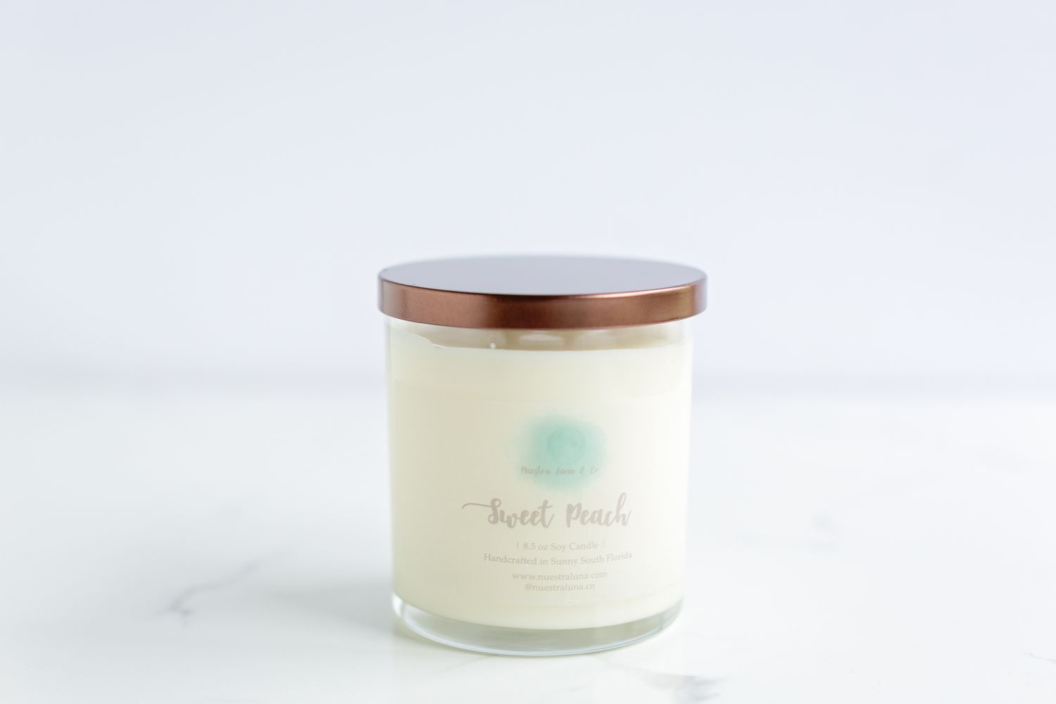 White candle in a glass jar with wooden lid displayed on marble surface.
