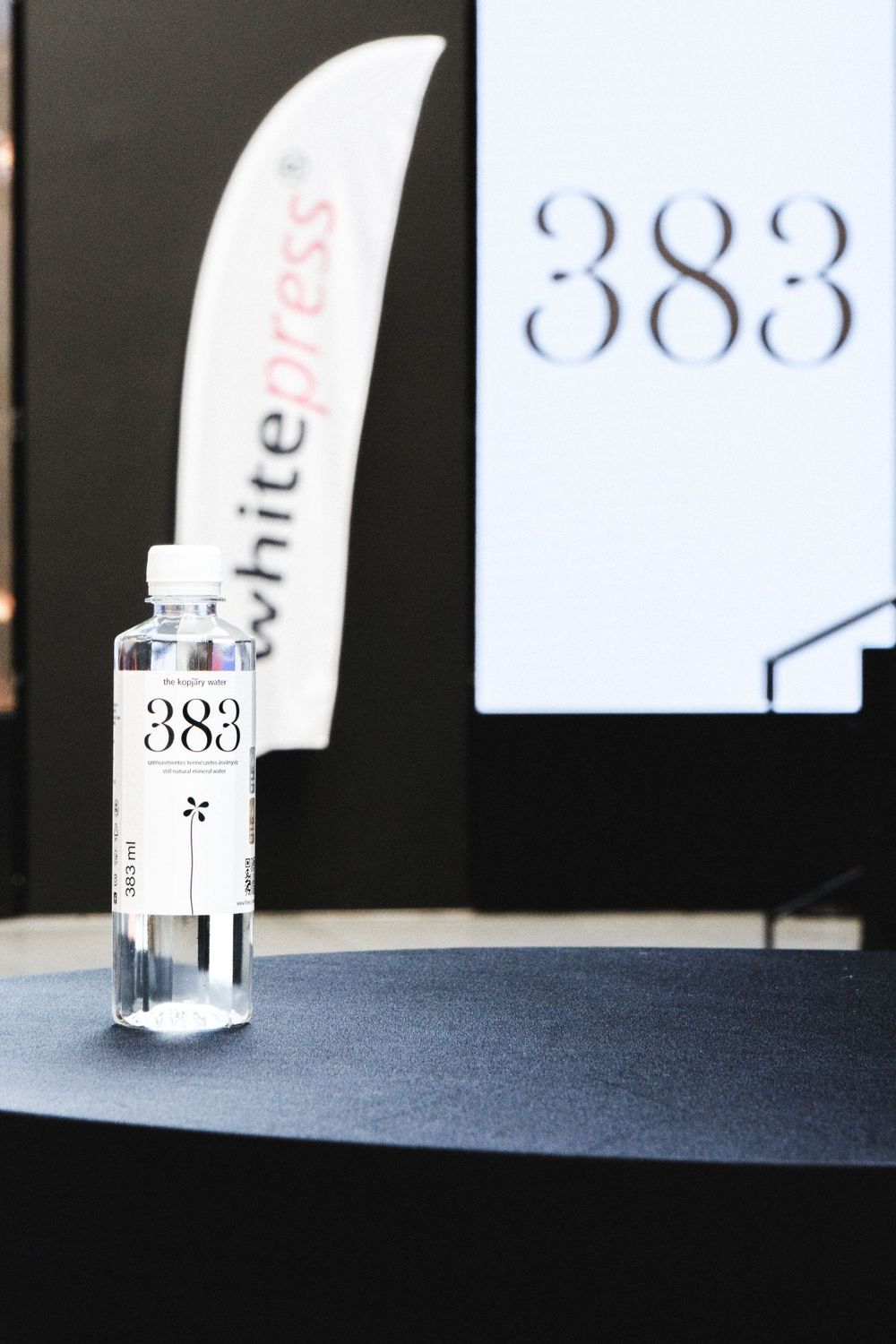 Clear glass vial with number 383 displayed next to white text against a black background.