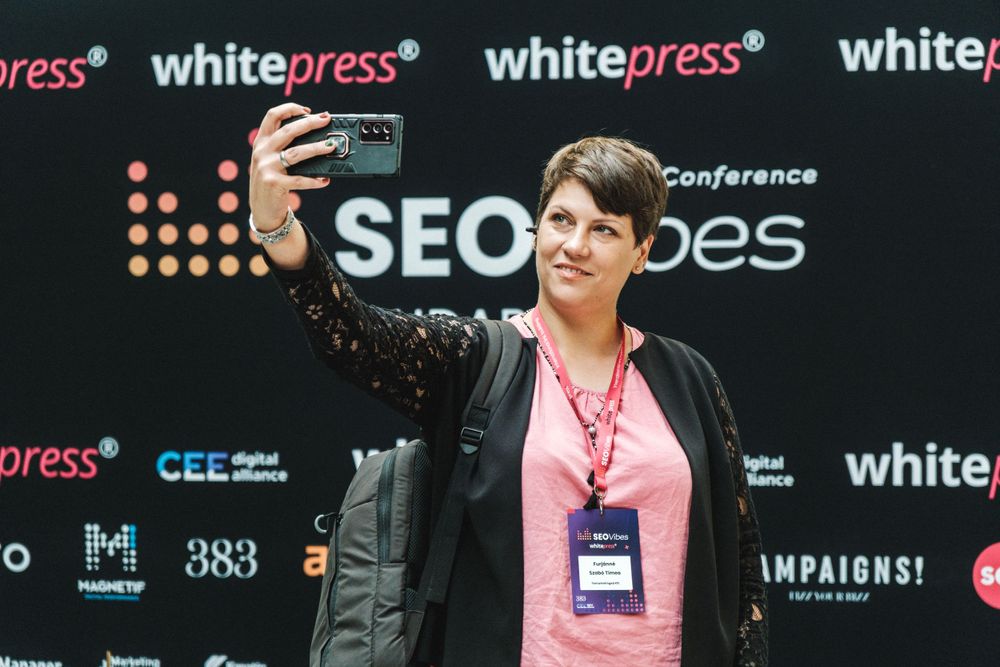 Conference attendee taking selfie in front of SEO Vibes event backdrop.