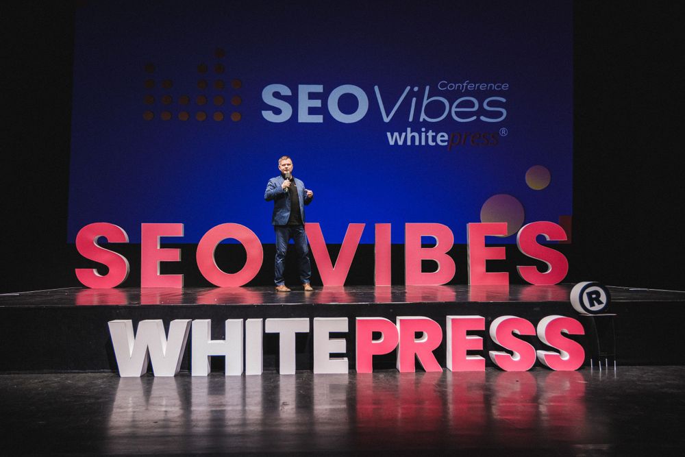 Large red and white SEO Vibes Whitepress text display on dark stage during presentation.