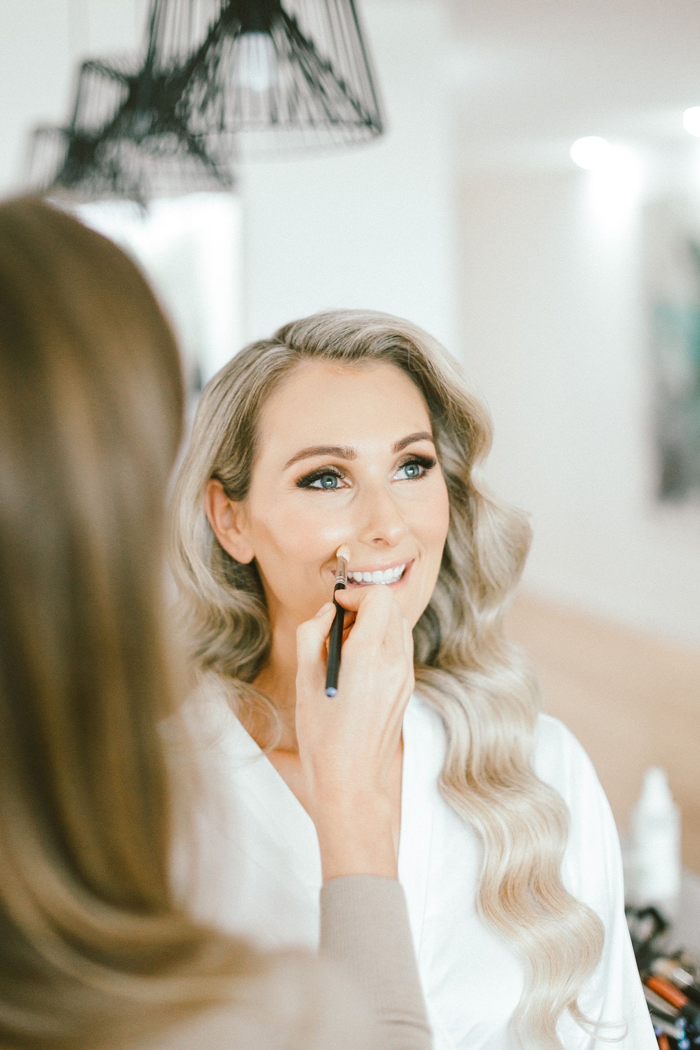 Professional makeup application in progress in bright modern setting.