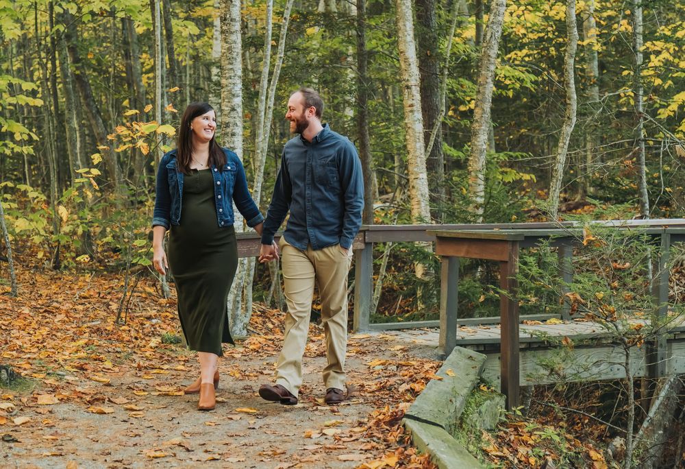 Couple walking hand in hand on wooden boardwalk through autumn forest.