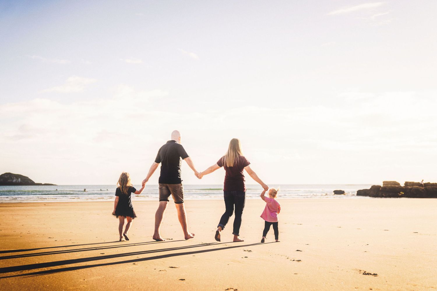 Muriwai Beach family photo, holding hands on a sunny day