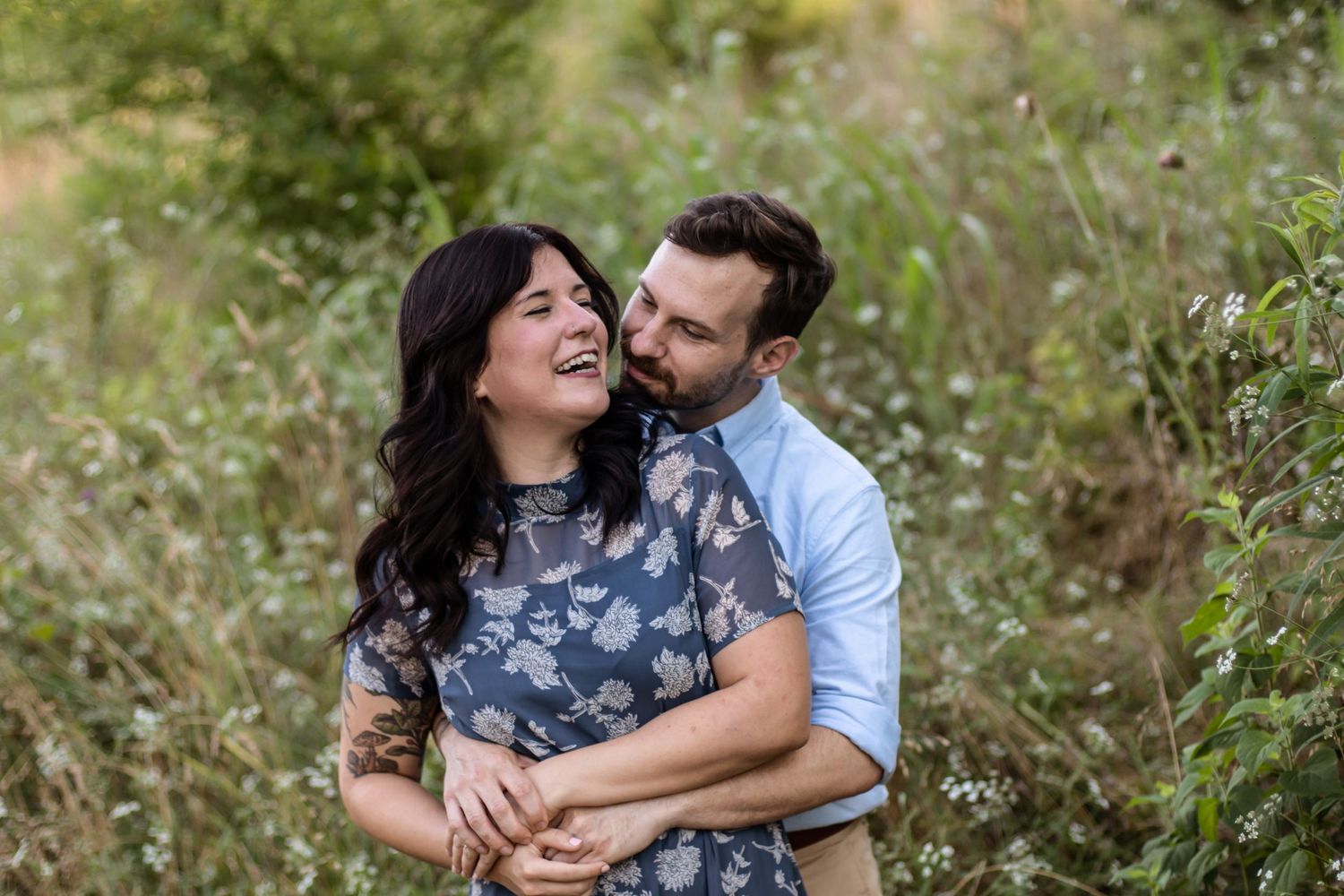 Happy couple laughing together in blooming wildflower meadow.