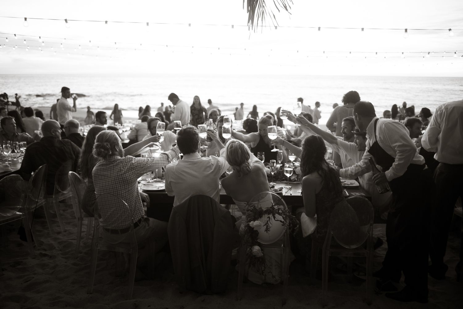 black and white image of guests raising glasses at a beach wedding reception in Sayulita, Mexico