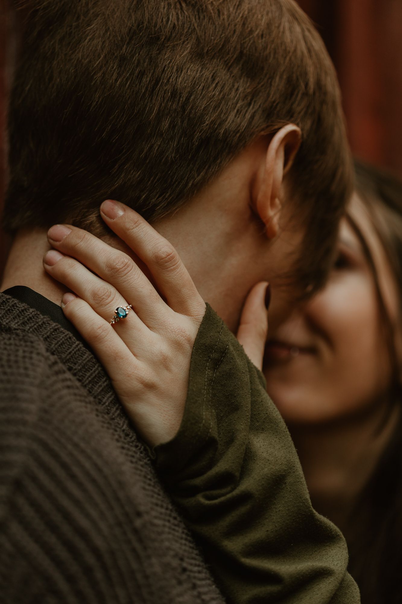 Close-up shot of hands with engagement ring in moody dark lighting.