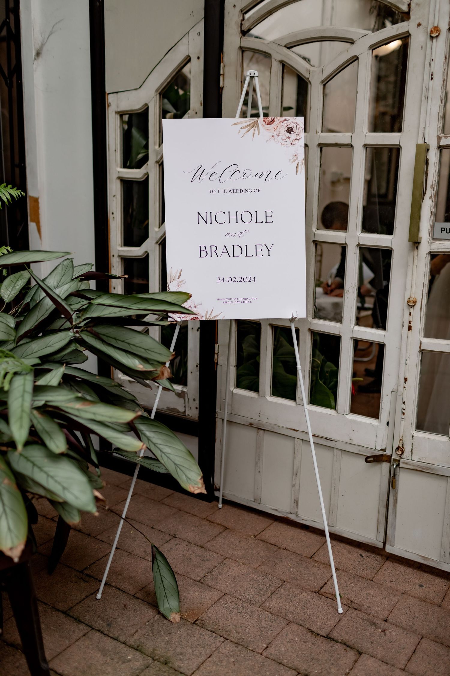 Elegant wedding welcome sign on easel display with floral accents.