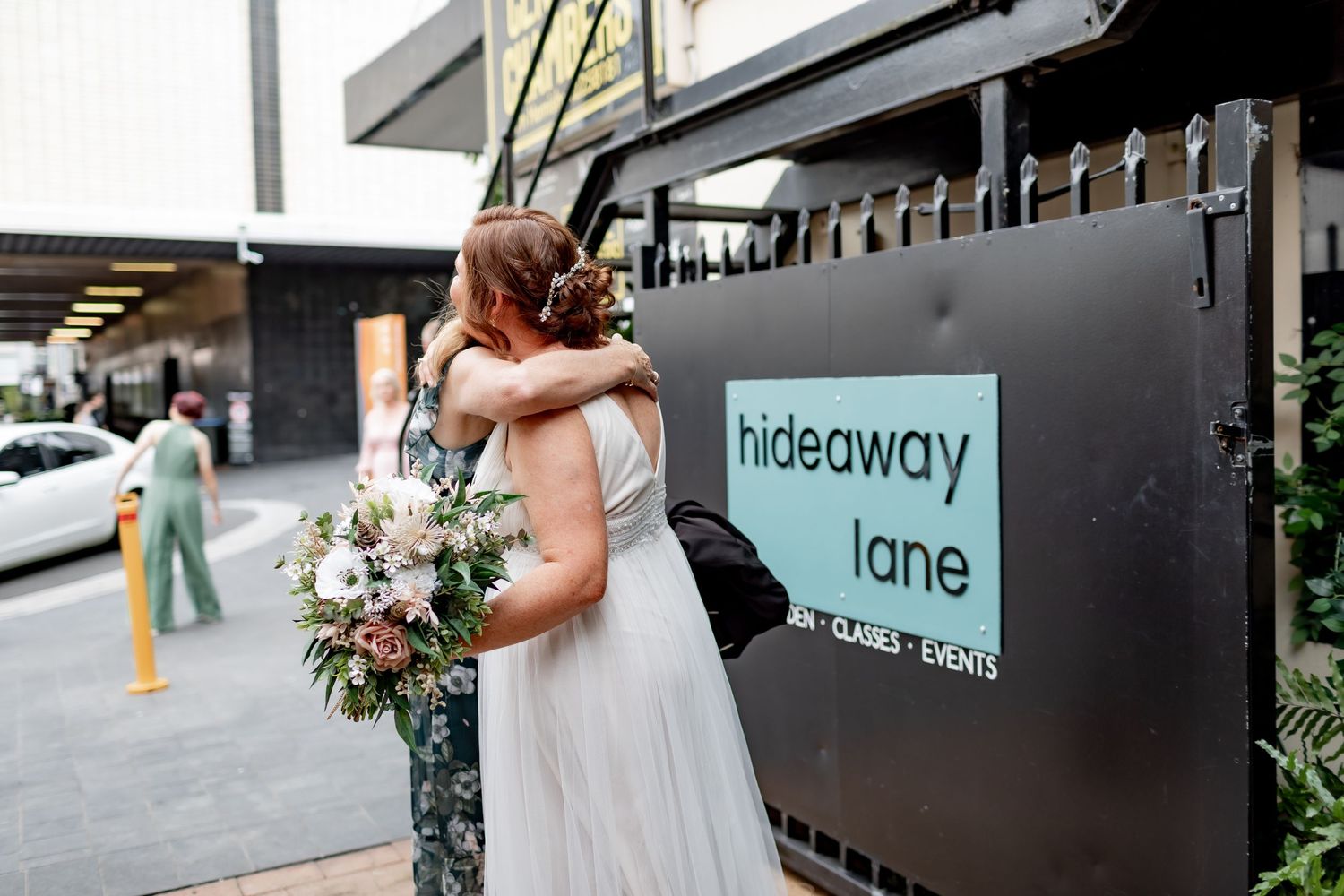 Couple embracing at Hideaway Lane venue with floral bouquet.