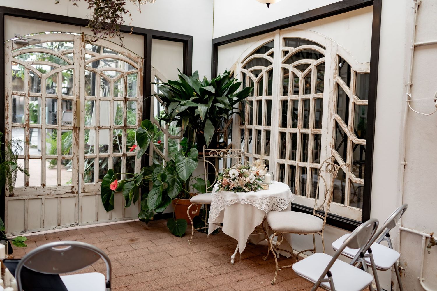 Romantic garden-style venue with arched windows and lush greenery.