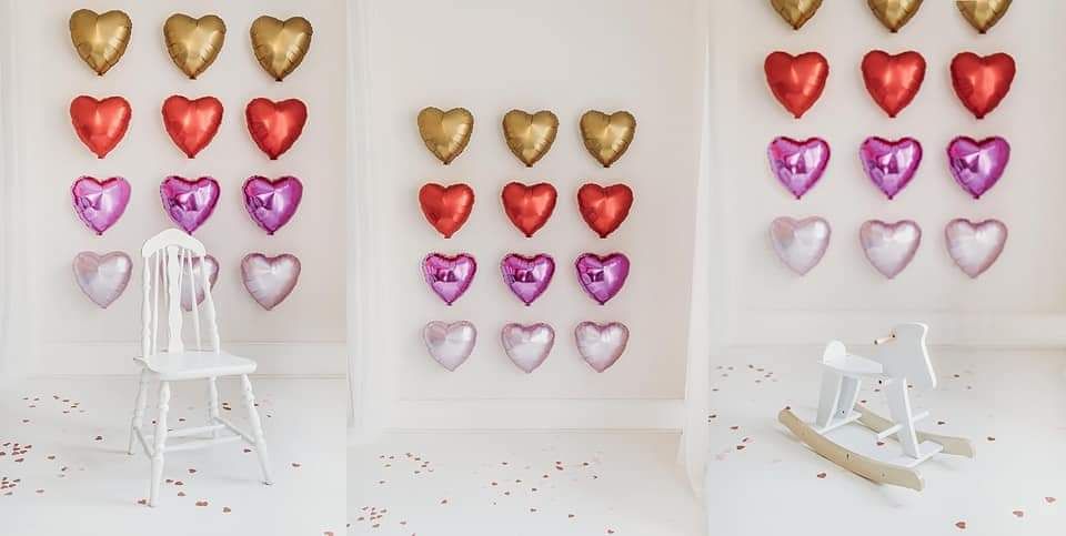 Heart-shaped metallic balloons in pink, red, and gold arranged in rows on white backdrop.