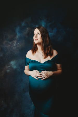 Maternity photoshoot featuring elegant poses against a dark background with blue accents.