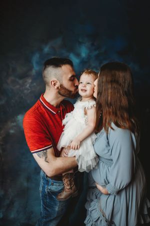 Family portrait in studio with red and gray outfits against moody blue background.