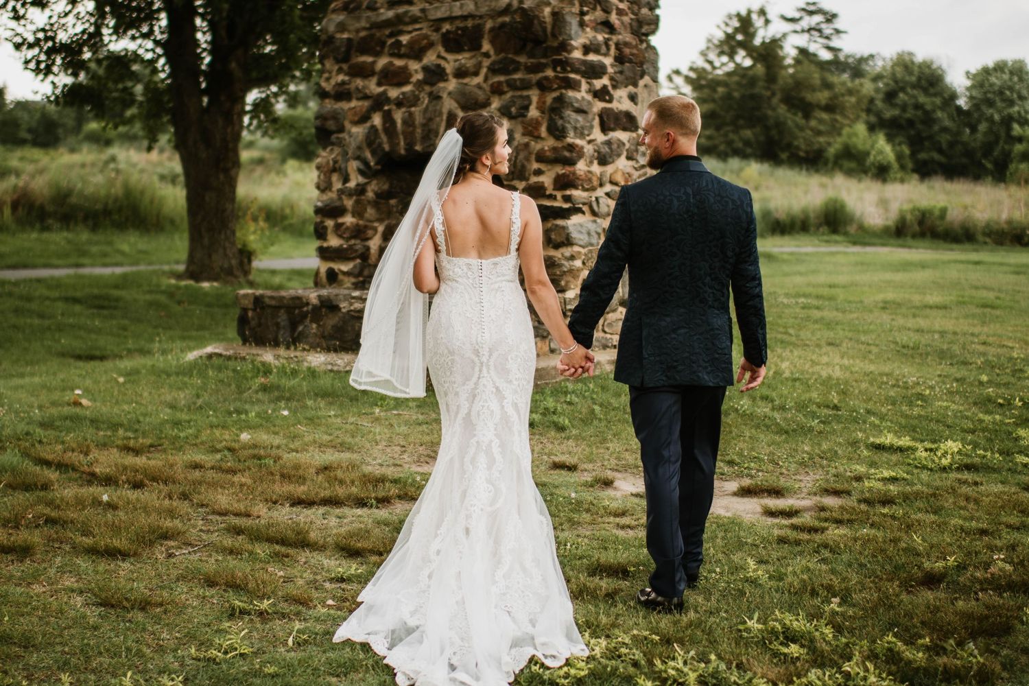 Couple walking through stone ruins in an outdoor wedding setting.