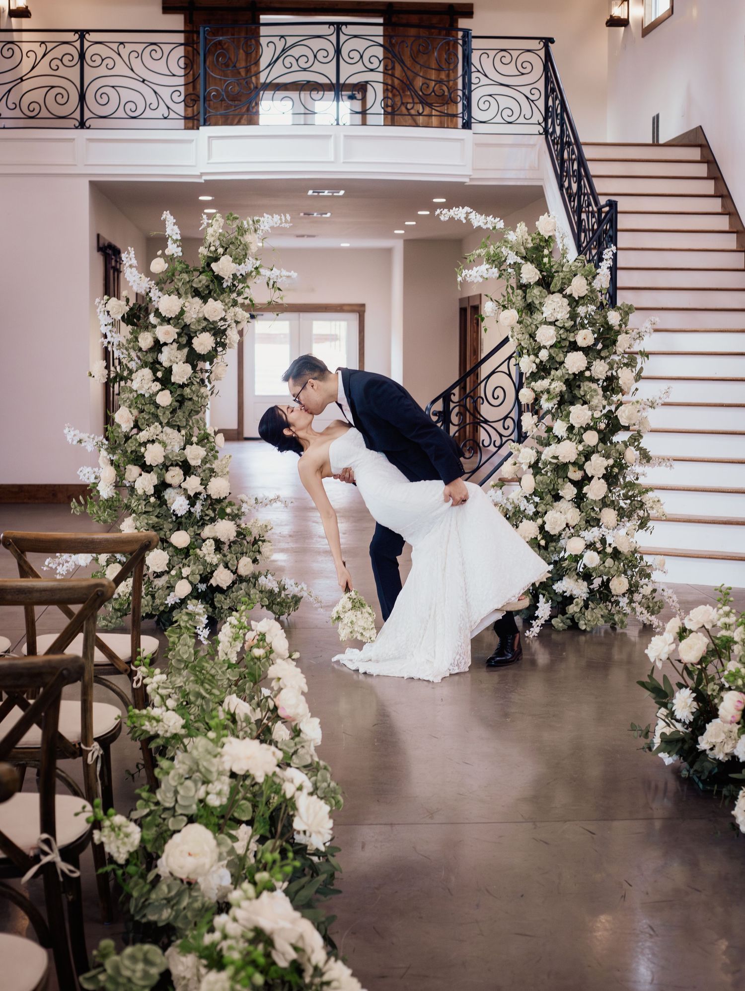 Wedding at Primrose Hill with ivory dress, sage colored flowers and arches, and groom in royal blue suit.