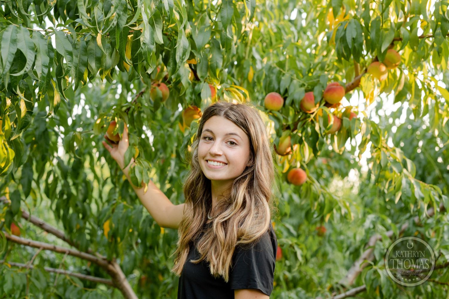 A joyful moment captured among the peach trees with sunlight filtering through the branches.