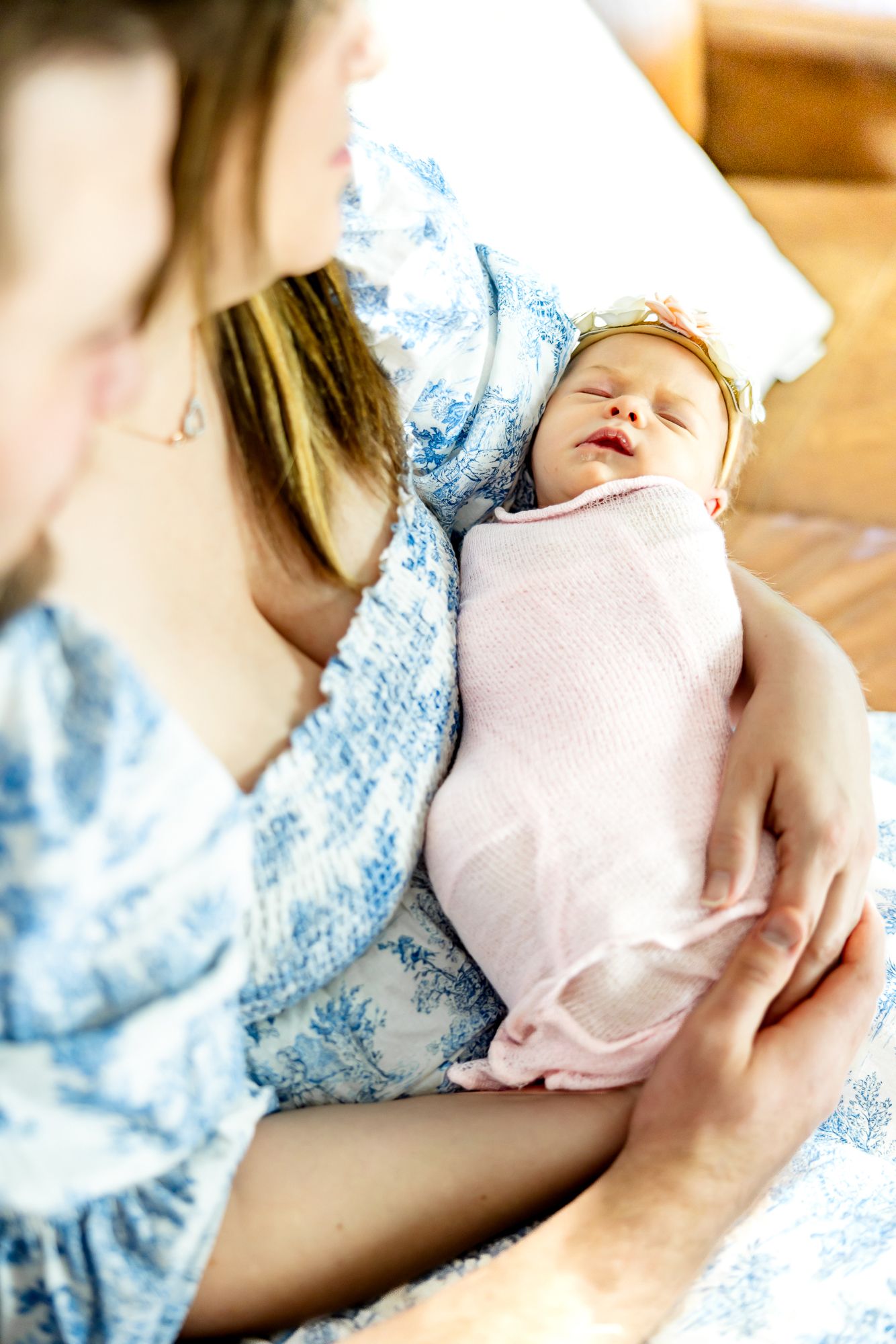 Focus on baby girl sleeping in mom's arms as parents gaze at her during lifestyle newborn photos in Colorado Springs.