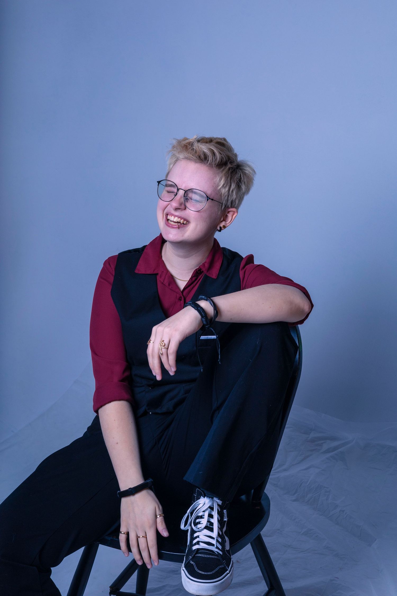 Person wearing red polo shirt and glasses sitting relaxed in black chair.