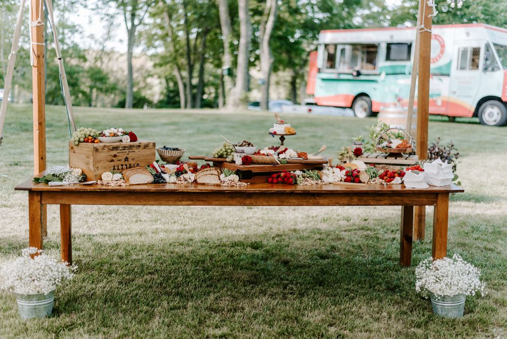 Outdoor wedding reception setup with wooden tables and delicate floral arrangements.