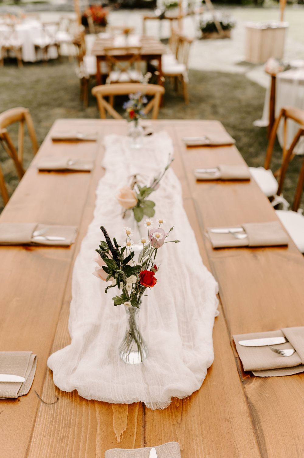 Wedding table settings with natural linen runners and delicate floral arrangements on wooden tables.