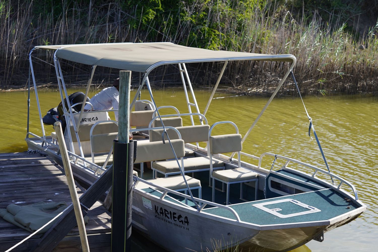 Small fishing boat with canopy cover docked at wooden pier.