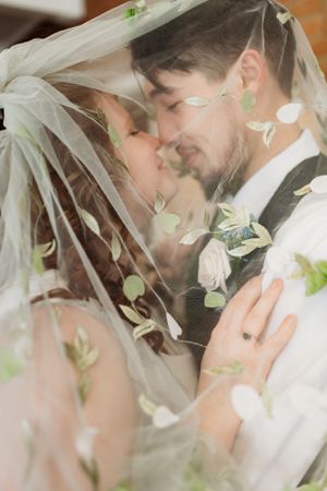 Romantic close-up through floral veil during wedding ceremony.
