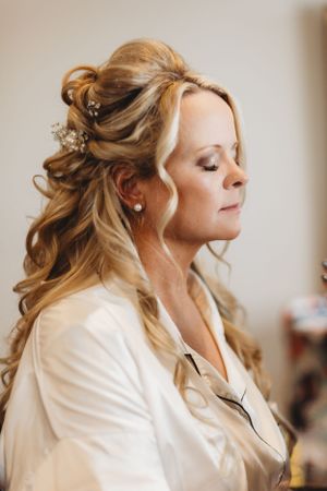 Elegant bridal hair styling features soft waves and decorative pins in blonde updo.