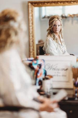 Bridal preparation moment captured in mirror reflection during wedding day preparations.
