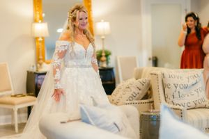 A bride in a beautiful lace wedding gown with long sleeves twirls in an elegant room.