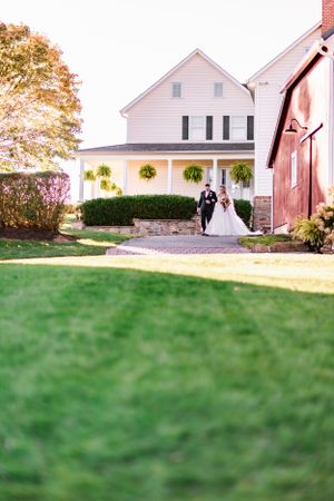 White farmhouse wedding venue with red barn and manicured lawn in autumn.
