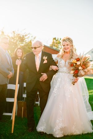 Sunset wedding ceremony with rustic decor and autumn-colored bouquet.