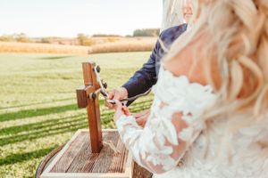 Wooden cross detail during rustic outdoor wedding ceremony with white lace dress in view.