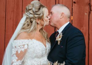 Romantic wedding portrait against rustic red barn background.