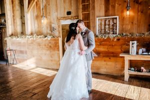 A romantic wedding dance in a rustic barn venue with wooden walls and string lights.