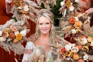 Bridal portrait framed by autumn-colored dried flowers and decorative elements.