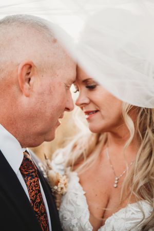 Intimate close up wedding moment captured under flowing white veil.