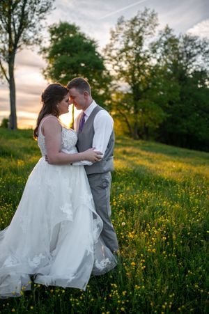 A romantic sunset portrait of newlyweds embracing in a field of yellow wildflowers.