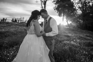 Black and white sunset portrait of newlyweds in an intimate embrace among wildflowers.